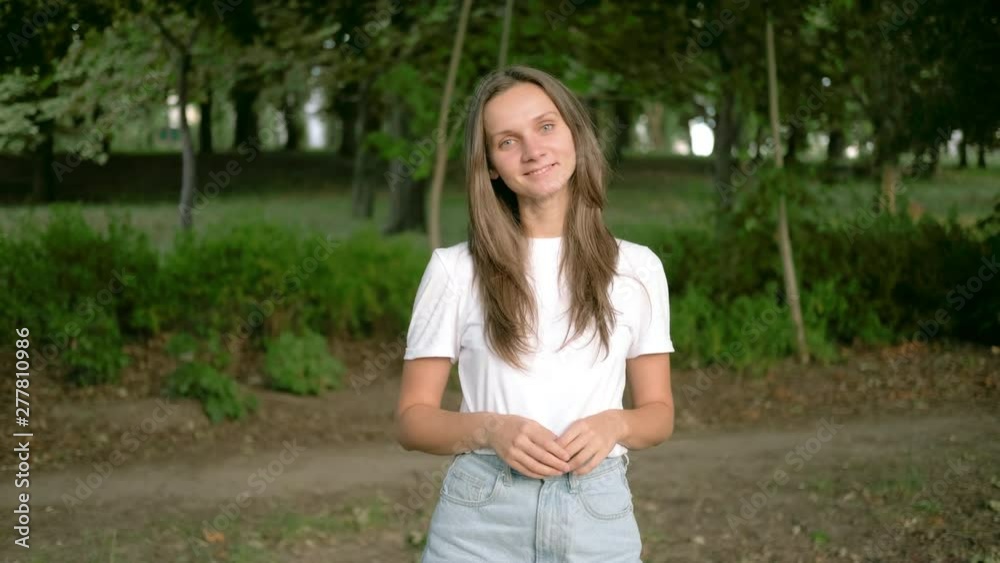 A young European brunette woman in the park is looking forward and smiling. Close up portrait A young European brunette woman in the park is looking forward and smiling. Close up portrait