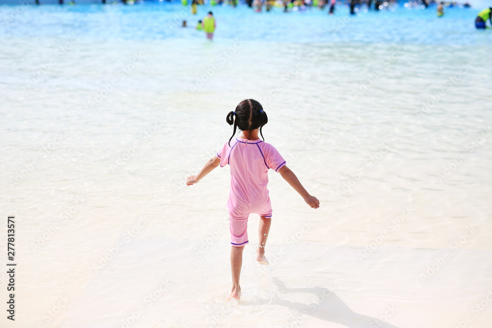 Little Asian child girl enjoys and running into big Swimming pool outdoor on holidays. Rear view children having fun. Little Asian child girl enjoys and running into big Swimming pool outdoor on holidays. Rear view children having fun.