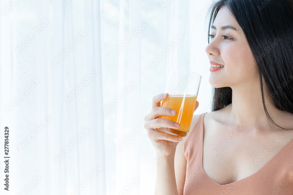 Beautiful beauty woman Asian cute girl feel happy drinking orange juice for good health in the morning , enjoying time in her home white bedroom background - lifestyle beauty woman concept Beautiful beauty woman Asian cute girl feel happy drinking orange juice for good health in the morning , enjoying time in her home white bedroom background - lifestyle beauty woman concept