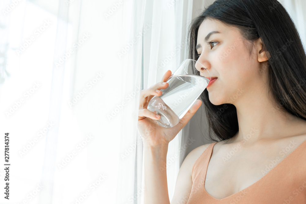 Beautiful beauty woman Asian cute girl feel happy drinking Clean drink water for good health in the morning , enjoying time in her home white bedroom background - lifestyle beauty woman concept Beautiful beauty woman Asian cute girl feel happy drinking Clean drink water for good health in the morning , enjoying time in her home white bedroom background - lifestyle beauty woman concept