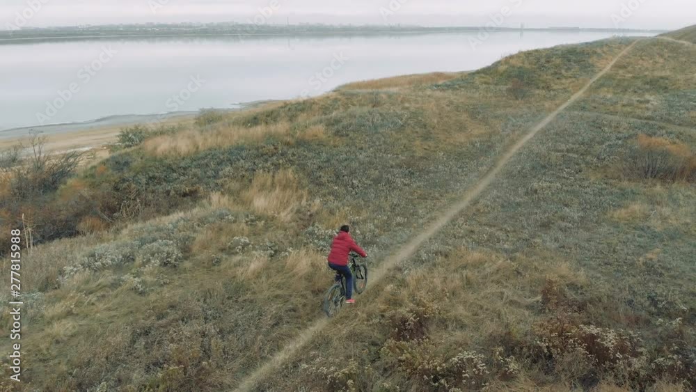 Man riding mountain bike near the lake in autumn nature. Shooting from drone Man riding mountain bike near the lake in autumn nature. Shooting from drone