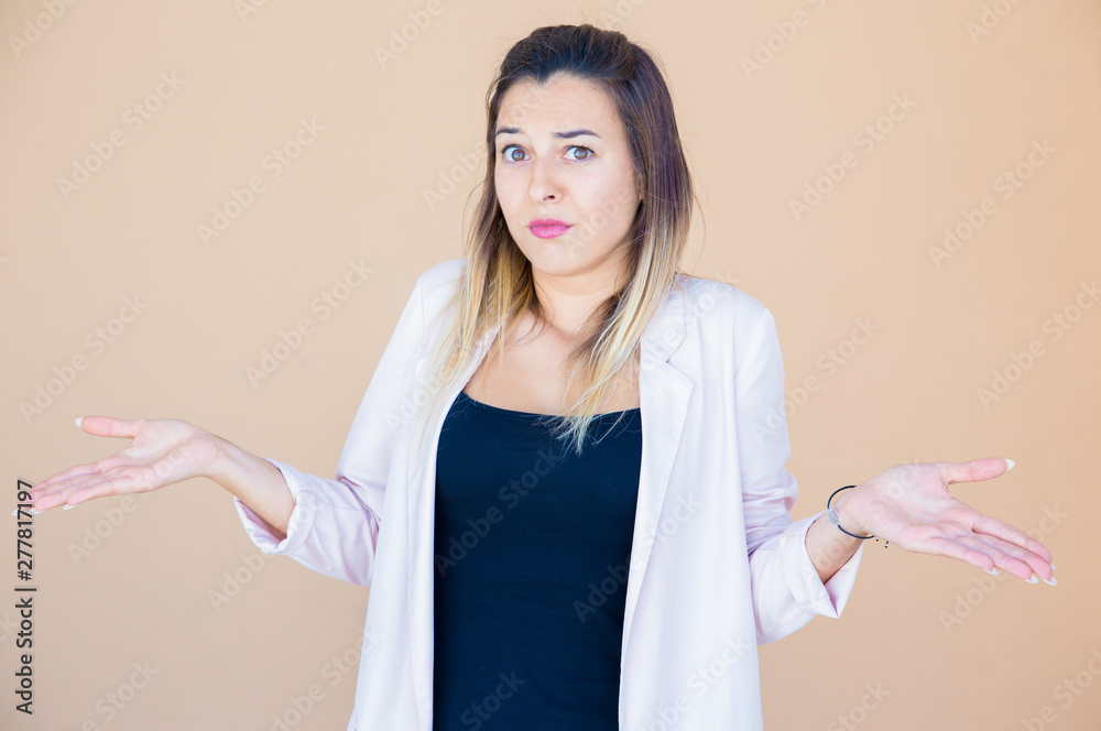 Puzzled lady shrugging shoulders. Clueless confused young woman in white casual jacket opening hands and expressing uncertainly. Unsure concept Puzzled lady shrugging shoulders. Clueless confused young woman in white casual jacket opening hands and expressing uncertainly. Unsure concept