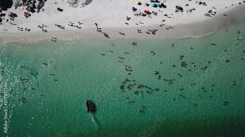 Drone view of people inside the blue ocean, and some boats in a tropical beach Pontal do Atalaia, Arraial do Cabo, Rio de janeiro