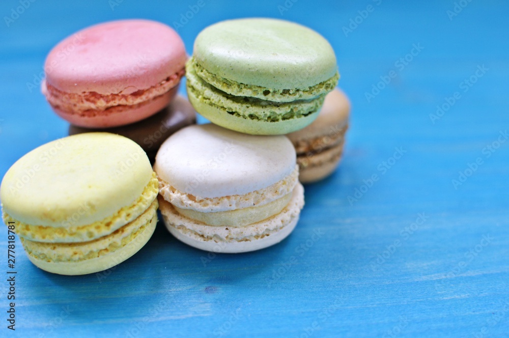 Pile of colorful macaroons on blue background. Close up, copy text. Pile of colorful macaroons on blue background. Close up, copy text.