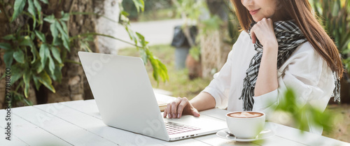 Obraz na plátně Beautiful young teenage woman freelance work with laptop with a cup of latte sun
