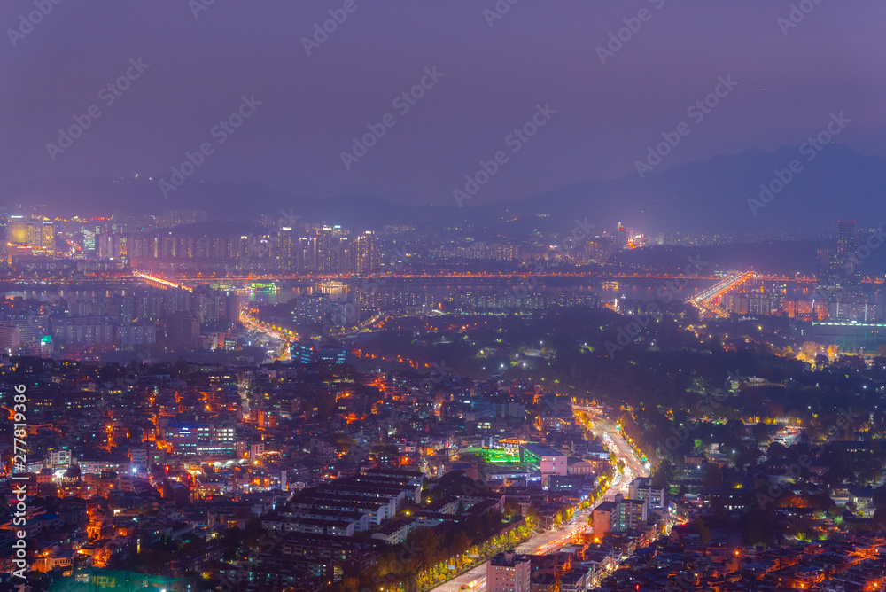 The light of city in the mist of night time. Picture with grain and color from film simulation filter. 