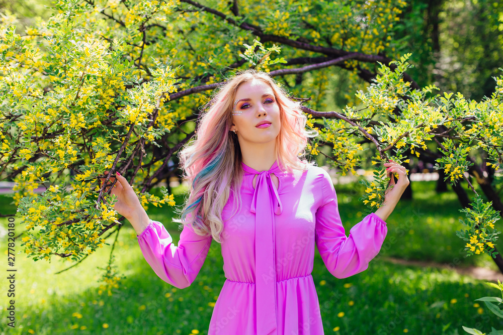 Beautiful girl with colorful dyed hair and perfect makeup and hairstyle standig next blooming barberry bush with yellow flowers Beautiful girl with colorful dyed hair and perfect makeup and hairstyle standig next blooming barberry bush with yellow flowers