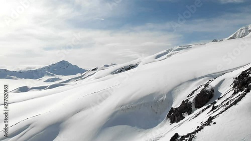 Aerial view of a winter mountain landscape. The snow-covered rocky slopes of the resort of the southern Elbrus region with ski tracks on the snow. Winter sports concept