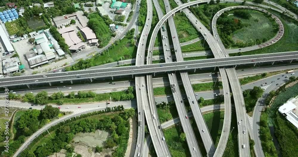 4K. Aerial view of road interchange of highway intersection with busy urban traffic speeding on the road. Junction network of transportation taken by drone.