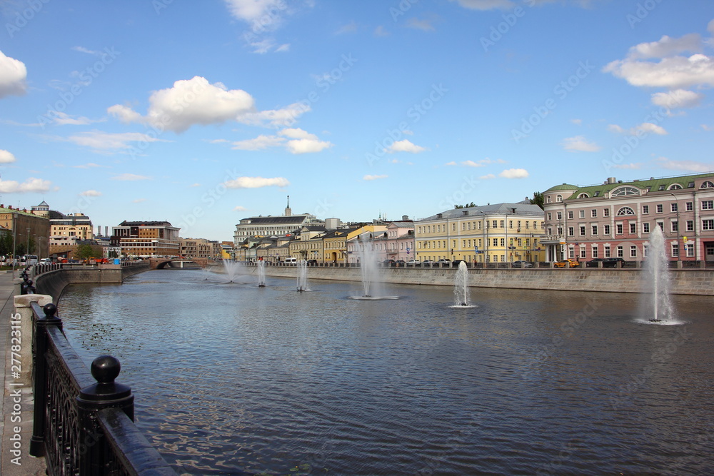 Beautiful fountains on the Vodootvodny canal in Moscow and old houses on Kadashevskaya embankmentvon a Sunny summer day on blue sky with white clouds background, view from Bolotnaya square