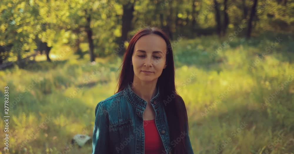 Nice girl goes through the forest and smiles. Summer walk in the forest. Portrait view. Nice girl goes through the forest and smiles. Summer walk in the forest. Portrait view.