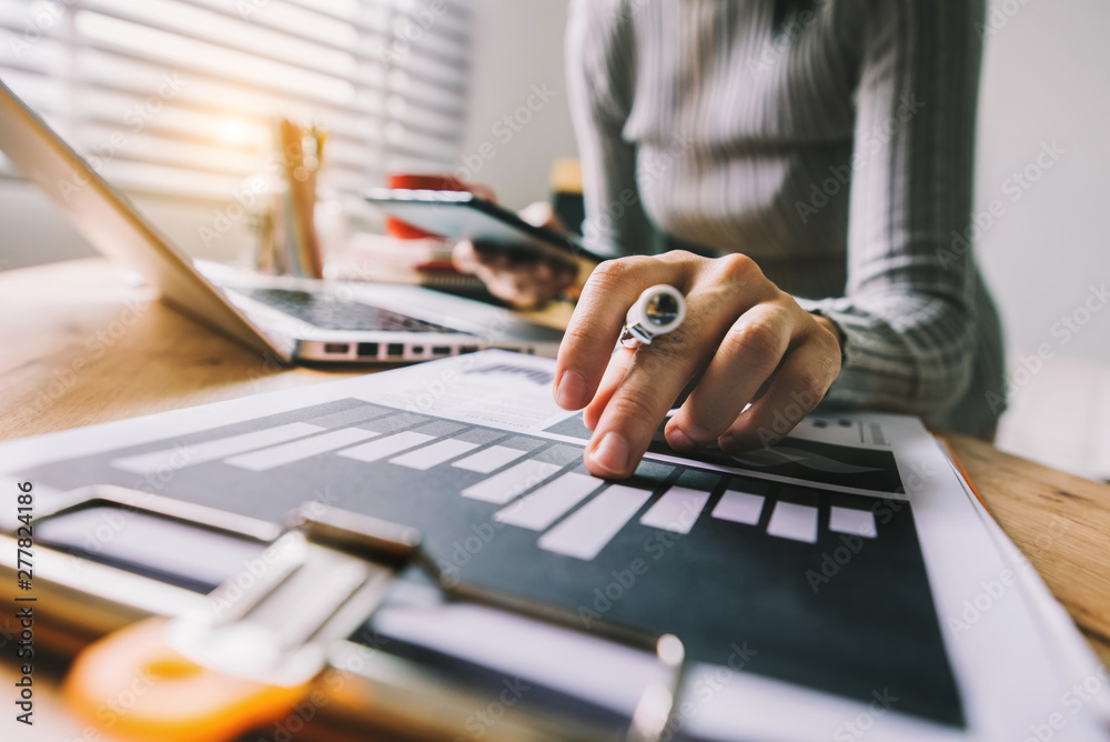 business documents on office desk with laptop and smart phone and graph business diagram and man working in morning light business documents on office desk with laptop and smart phone and graph business diagram and man working in morning light