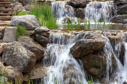 Waterfall between stone boulders, landscape design element.