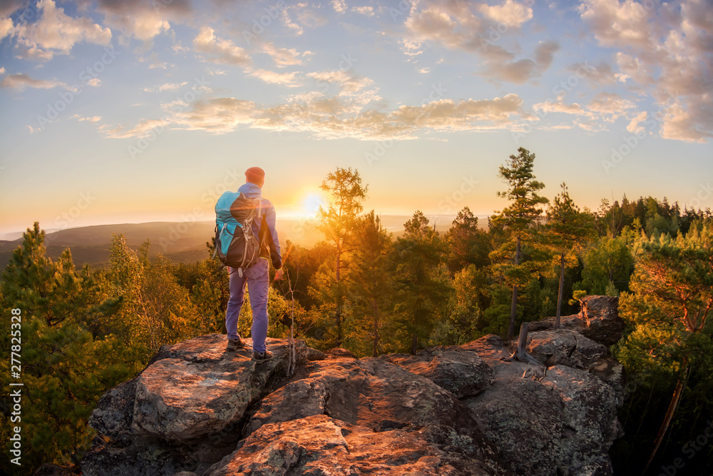 Hiker with backpack standing on a rock and enjoying sunset on mauntain Hiker with backpack standing on a rock and enjoying sunset on mauntain