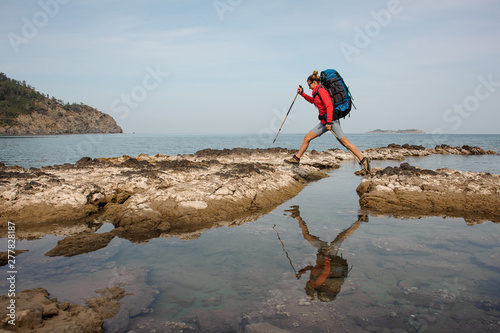 Woman with backpack treks on sea coast photo