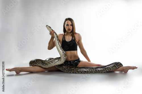 Beautiful gymnastics woman with python in studio