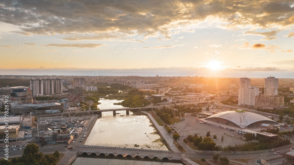 South Ural capital Chelyabinsk; summer evening with cloudy sky; drone flying forward to city center over river, embankment zone; transportation system, recreation area, urban life in industrial city