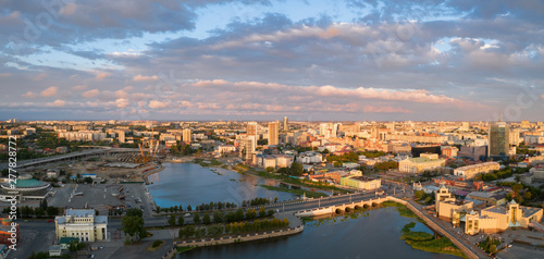 South Ural capital Chelyabinsk; summer evening with cloudy sky; drone flying forward to city center over river, embankment zone; transportation system, recreation area, urban life in industrial city