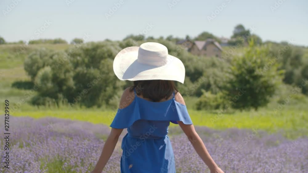 Playful carefree young female in blue dress and sun hat taking a walk in lavender blossoms, inviting to follow her, making beckoning gesture and smiling while enjoying outdoor leisure in countryside. Playful carefree young female in blue dress and sun hat taking a walk in lavender blossoms, inviting to follow her, making beckoning gesture and smiling while enjoying outdoor leisure in countryside.