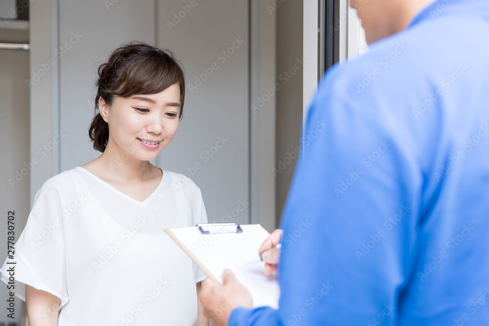 玄関でサインする女性 玄関でサインする女性