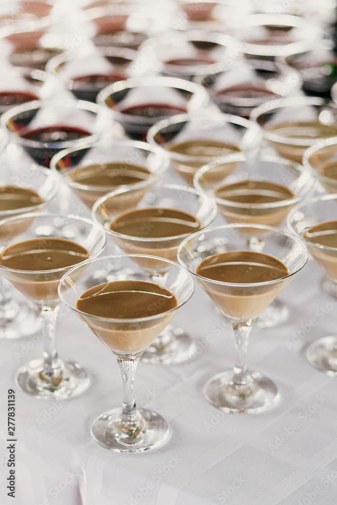 Martini rows on table at wedding reception. Cocktails and red and white martini in glasses at alcohol bar at wedding or christmas feast. Luxury catering Martini rows on table at wedding reception. Cocktails and red and white martini in glasses at alcohol bar at wedding or christmas feast. Luxury catering