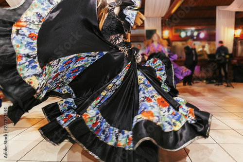 Beautiful gypsy girls dancing in traditional black floral dress at wedding reception in restaurant. Woman performing romany dance and folk songs in national clothing. Roma gypsy festival