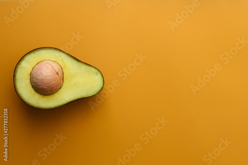 close up of avocado sliced in half on yellow background