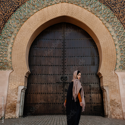Tourist by authentic gate in Meknes, Morocco
