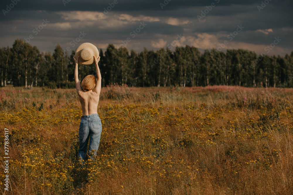 Woman in jeans and with straw hat in field of flowers. Woman in jeans and with straw hat in field of flowers.