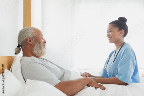Healthcare worker talking with old man in bed