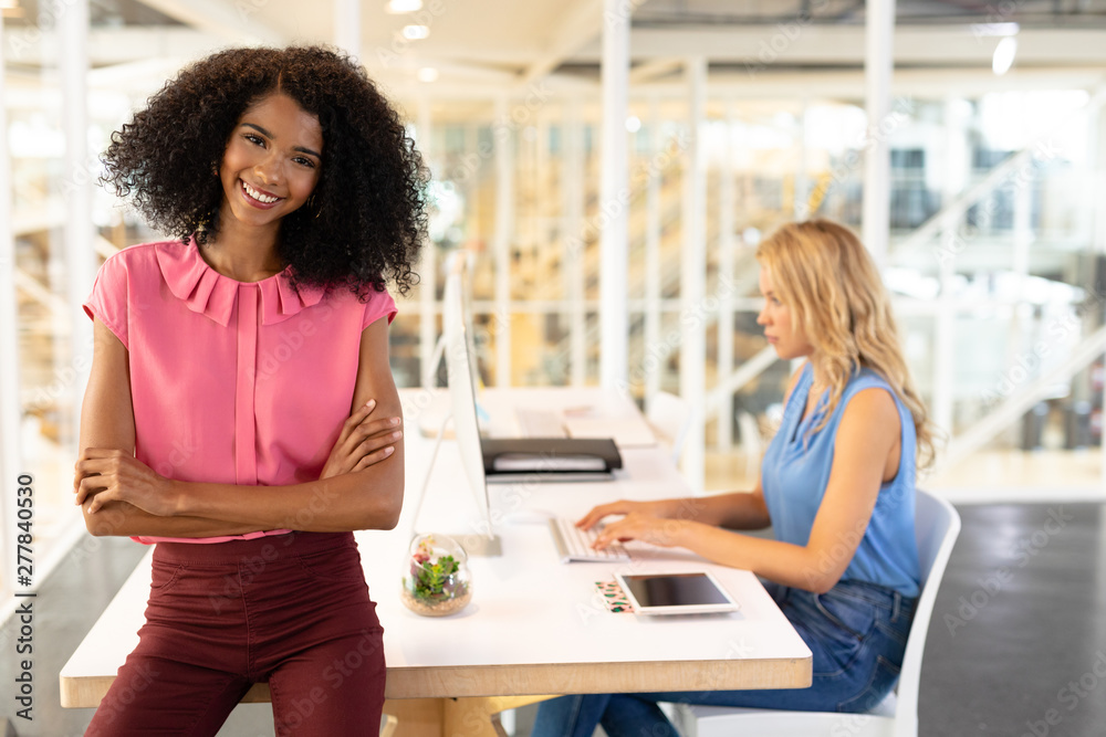 Female executive sitting with arms crossed at desk in office Female executive sitting with arms crossed at desk in office