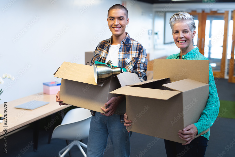 Male and female executives carrying cardboard boxes in office Male and female executives carrying cardboard boxes in office