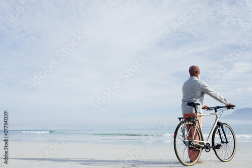 Man holding a bicycle on the beach