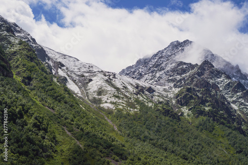 Beautiful summer sunny mountain landscape. The border between greenery and snow.