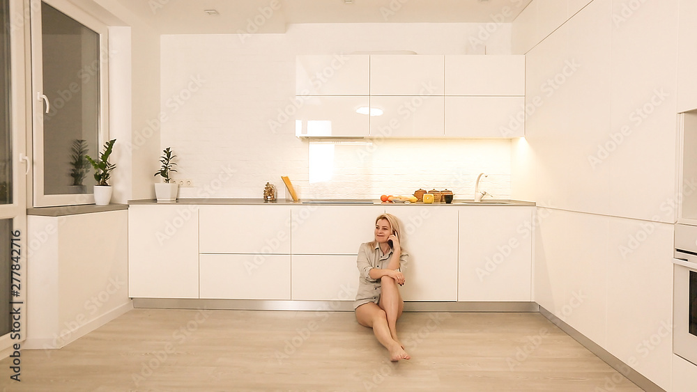 Happy young woman dancing in kitchen in the morning listening to music on smartphone Happy young woman dancing in kitchen in the morning listening to music on smartphone