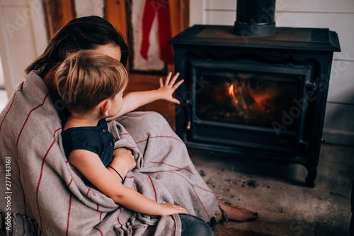 woman and toddler son sitting in front of fireplace photo