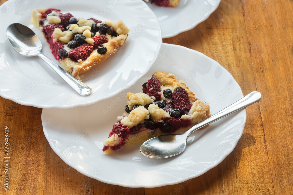Three slices of blueberry and raspberry tart on white plates 