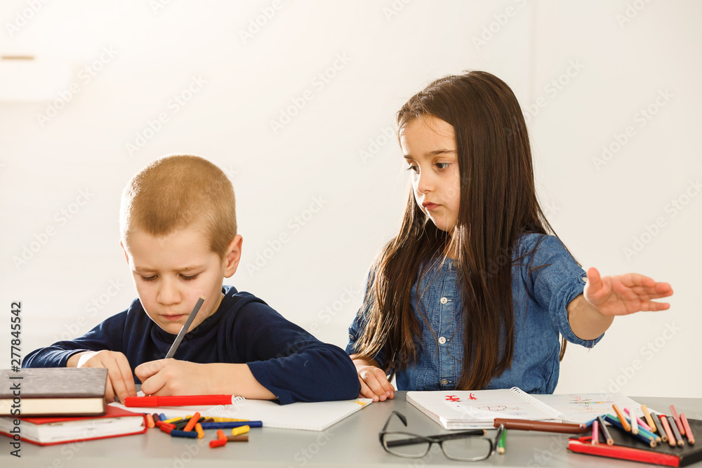 Portrait of two kids looking at workplace with schoolboys on background Portrait of two kids looking at workplace with schoolboys on background