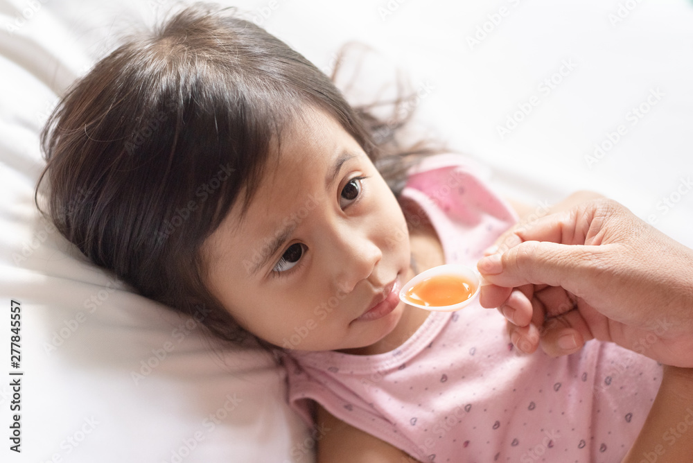 Unhappy asain girl when taking medicine syrup from her mother Unhappy asain girl when taking medicine syrup from her mother
