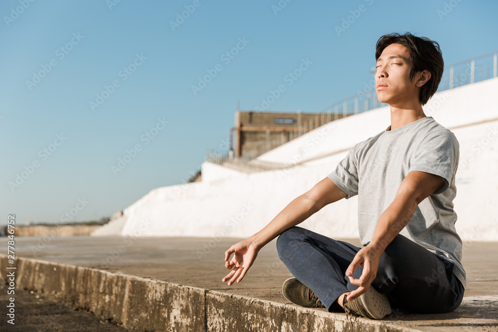 Calm healthy asian man doing yoga exercises at the beach Calm healthy asian man doing yoga exercises at the beach