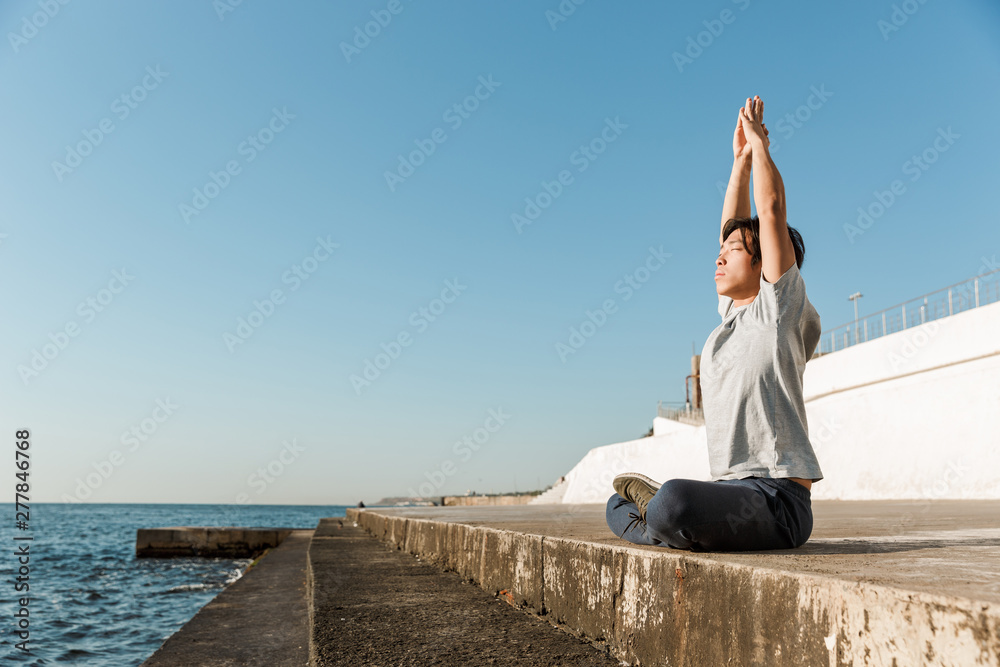 Calm healthy asian man doing yoga exercises at the beach Calm healthy asian man doing yoga exercises at the beach