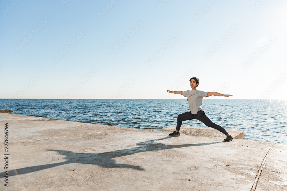 Calm healthy asian man doing yoga exercises at the beach Calm healthy asian man doing yoga exercises at the beach
