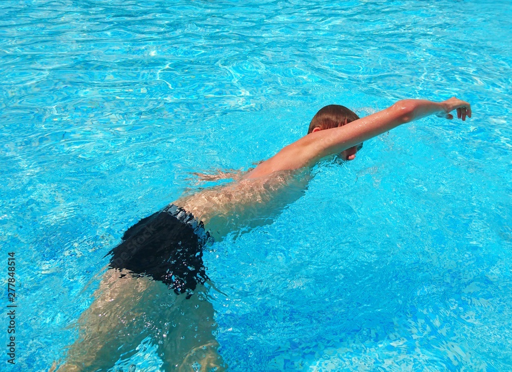 Teen guy swims in the pool