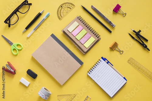 High angle view of various stationeries on yellow surface