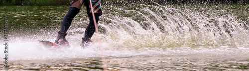 male athlete rides on a wakeboard on lake in summer © Shcherbyna