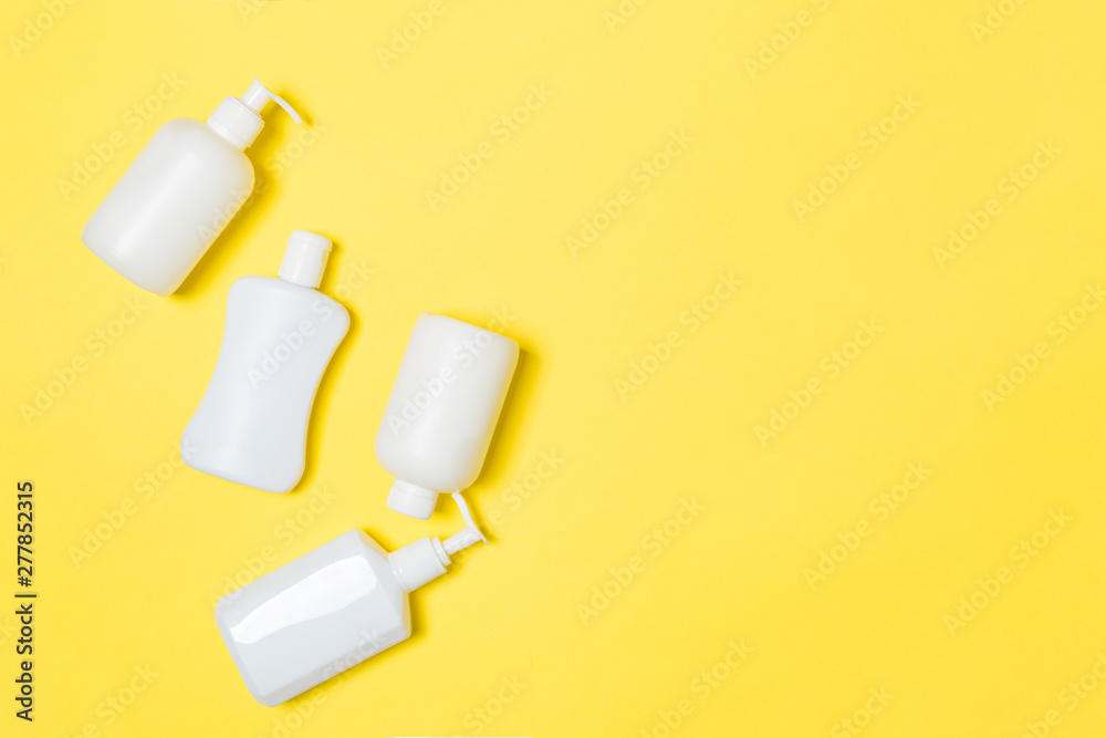 Set of White Cosmetic containers isolated on yellow background, top view with copy space. Group of plastic bodycare bottle containers with empty space for you design Set of White Cosmetic containers isolated on yellow background, top view with copy space. Group of plastic bodycare bottle containers with empty space for you design