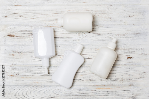 Set of White Cosmetic containers on wooden background, top view with copy space. Group of plastic bodycare bottle containers with empty space for you design