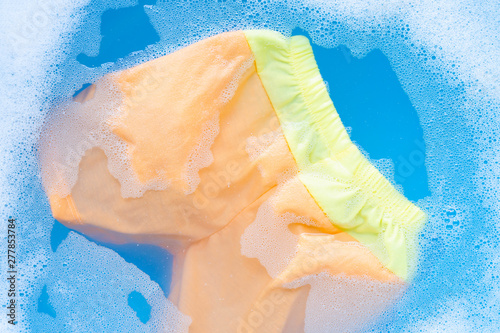 Yellow and orange baby shorts soak in baby laundry detergent water dissolution, washing cloth, Laundry concept.