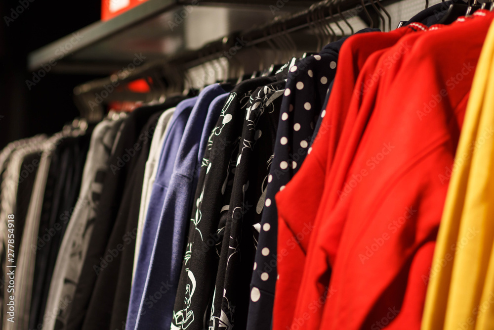 Colorful women's dresses on hangers in a retail shop. Fashion and shopping concept Colorful women's dresses on hangers in a retail shop. Fashion and shopping concept