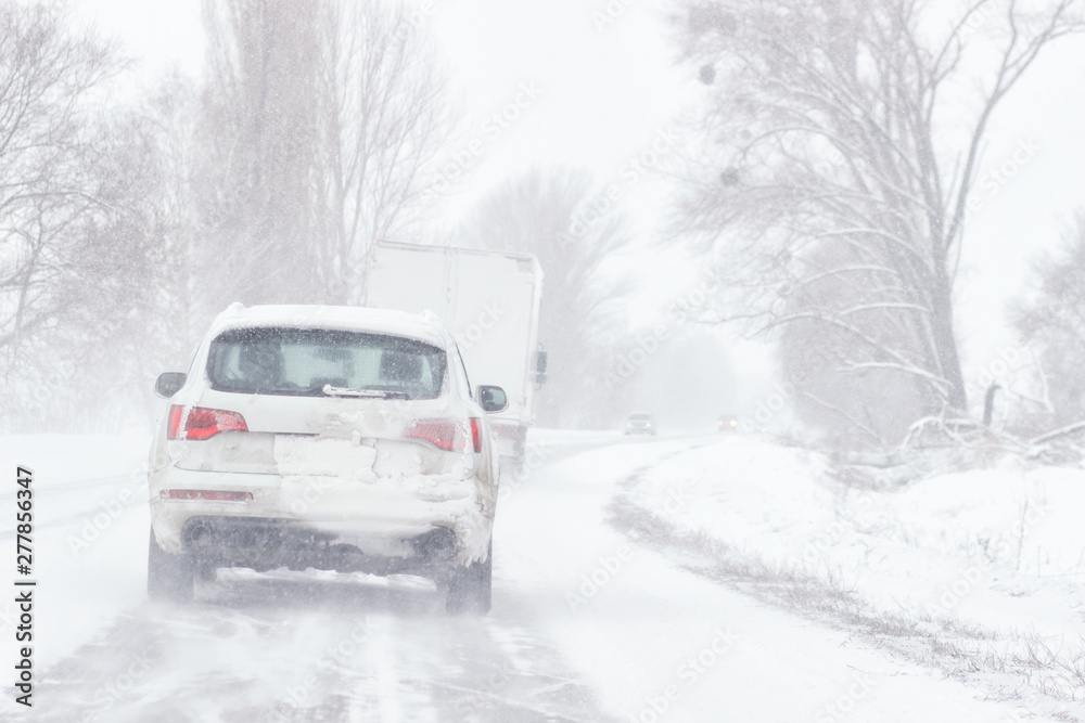 Snow covered road, winter driving with sign - slippery